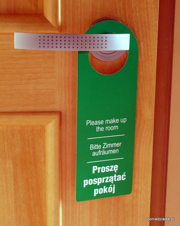 Zawieszka hotelowa na drzwi strona z białym napisem Proszę posprzątać pokój na zielonym tle.
