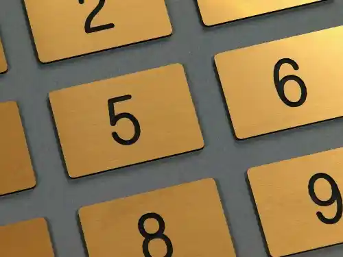 Kilka małych grawerowanych numerków w kolorze złotym szczotkowanym