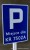 Tabliczka parkingowa zamontowana przy pomocy uchwytów montażowych. 