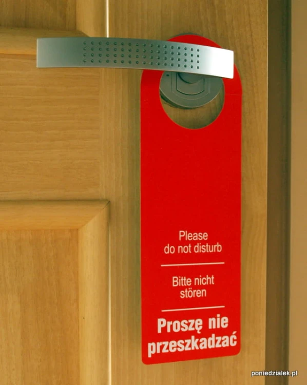 Zawieszka hotelowa na drzwi strona z białym napisem Proszę nie przeszkadzać na czerwonym tle.